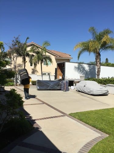 Movers carrying furniture in suburban driveway